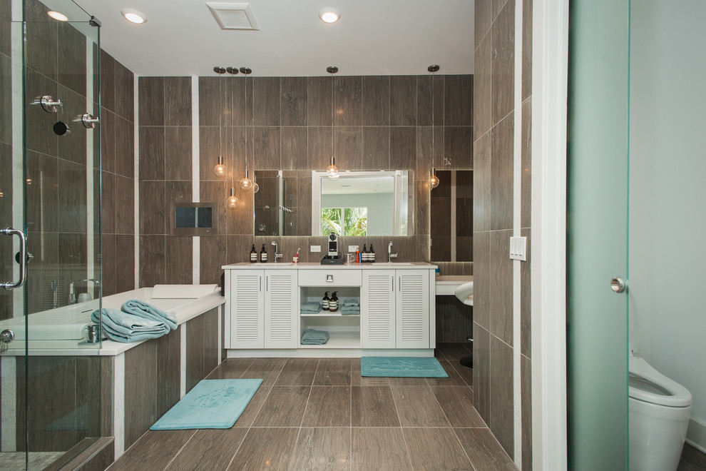 Large beach style master brown tile and porcelain tile porcelain tile and brown floor bathroom photo in Tampa with louvered cabinets, white cabinets, brown walls, a drop-in sink, a hinged shower door and a one-piece toilet