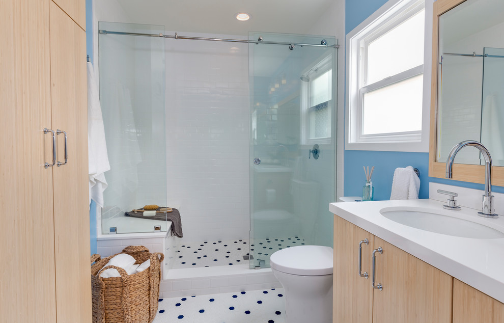 Inspiration for a medium sized contemporary ensuite bathroom in Los Angeles with flat-panel cabinets, light wood cabinets, an alcove shower, a two-piece toilet, blue tiles, blue walls, a submerged sink, engineered stone worktops, white floors, a sliding door, metro tiles and porcelain flooring.