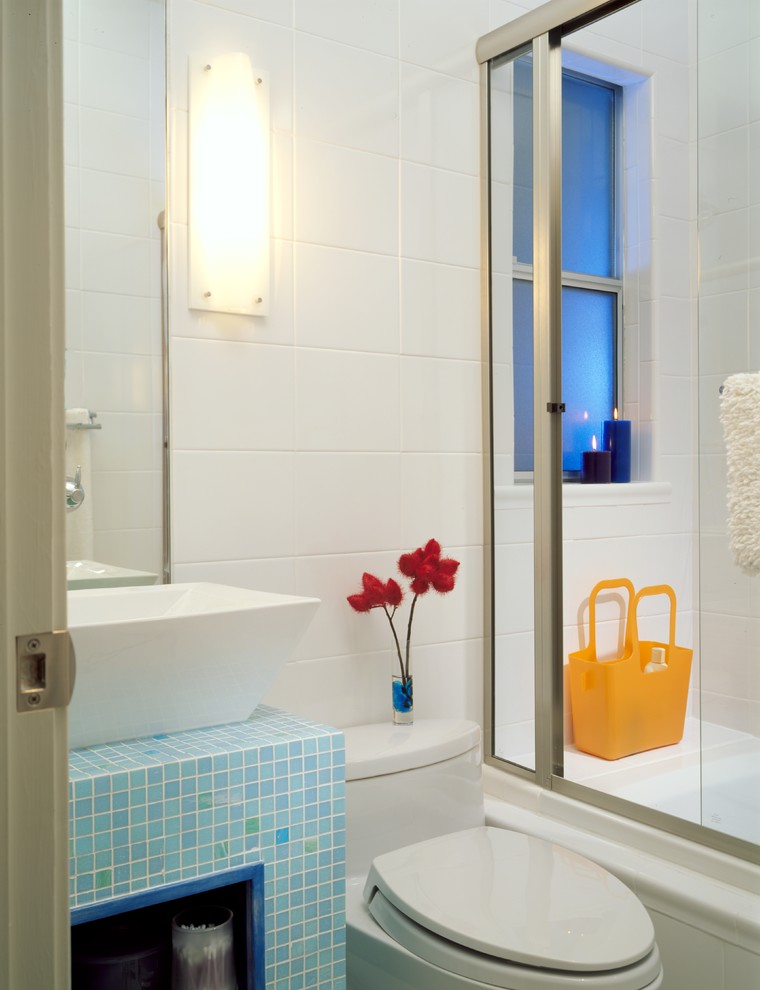 Aménagement d'une petite salle d'eau contemporaine avec un placard sans porte, des portes de placard bleues, une baignoire en alcôve, un combiné douche/baignoire, WC à poser, un carrelage blanc, des carreaux de céramique, un mur blanc, une vasque, un plan de toilette en carrelage, une cabine de douche à porte coulissante et un plan de toilette bleu.
