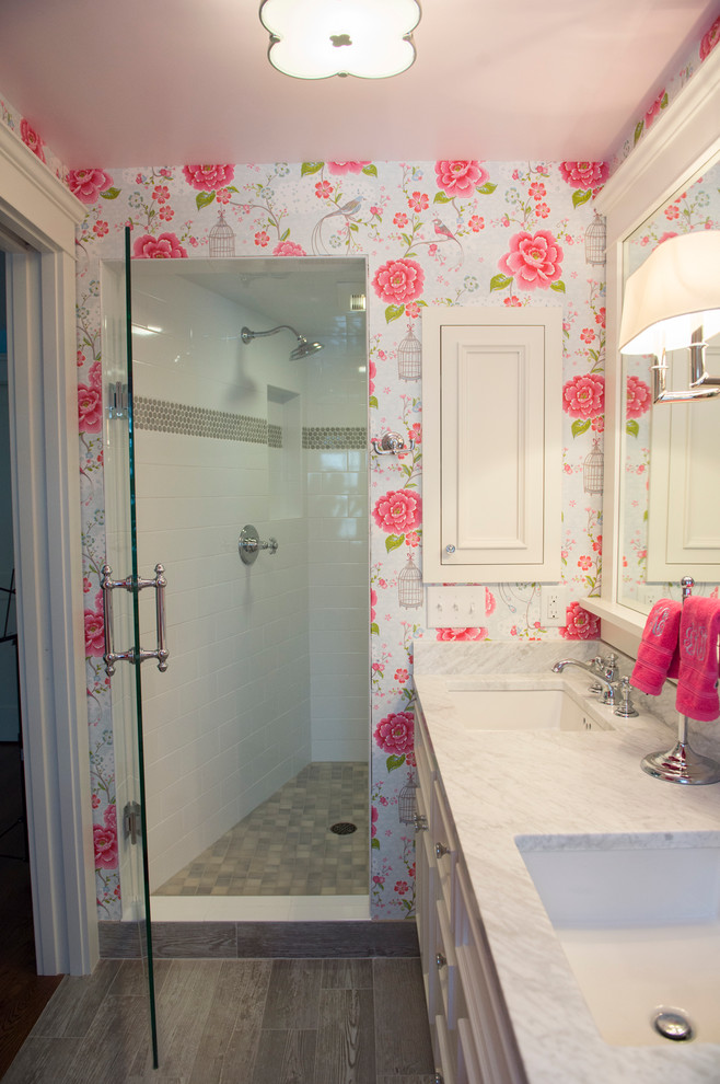 На фото: детская ванная комната среднего размера в классическом стиле с врезной раковиной, фасадами островного типа, белыми фасадами, мраморной столешницей, угловым душем, серой плиткой, плиткой кабанчик, розовыми стенами, полом из керамической плитки, раздельным унитазом, коричневым полом и душем с распашными дверями