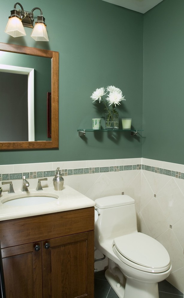 Kleines Klassisches Duschbad mit Schrankfronten im Shaker-Stil, dunklen Holzschränken, Toilette mit Aufsatzspülkasten, beigen Fliesen, Keramikfliesen, grüner Wandfarbe, Keramikboden, Unterbauwaschbecken, Mineralwerkstoff-Waschtisch und grünem Boden in New York