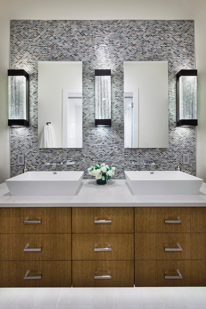 Bathroom - mid-sized eclectic master gray tile and mosaic tile marble floor and white floor bathroom idea in Denver with a vessel sink, flat-panel cabinets, light wood cabinets, solid surface countertops, a two-piece toilet, multicolored walls and a hinged shower door
