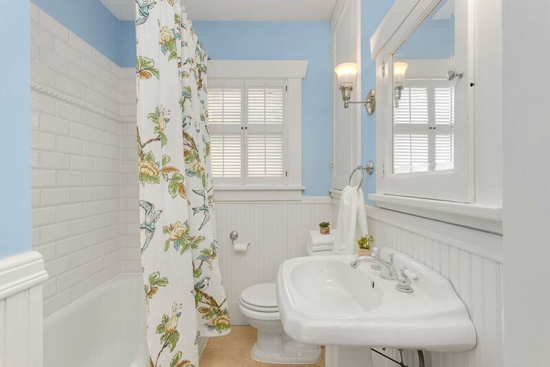 This is an example of a medium sized traditional shower room bathroom in Seattle with white cabinets, a corner bath, a shower/bath combination, white tiles, ceramic tiles, blue walls, ceramic flooring and a submerged sink.
