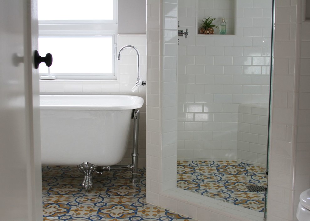 Klassisches Badezimmer mit weißen Fliesen, weißer Wandfarbe, Betonboden, Löwenfuß-Badewanne, Eckdusche, Keramikfliesen und Falttür-Duschabtrennung in Los Angeles