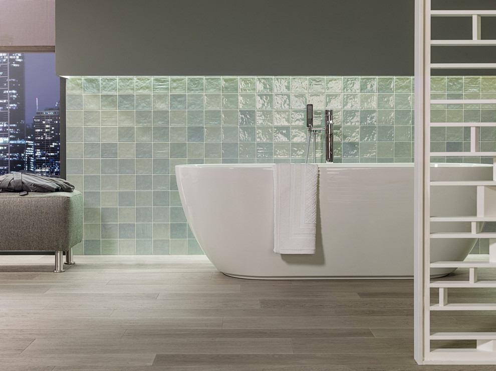Exemple d'une salle de bain tendance avec une baignoire indépendante, un carrelage vert, des carreaux de céramique, un mur gris et un sol en carrelage de porcelaine.