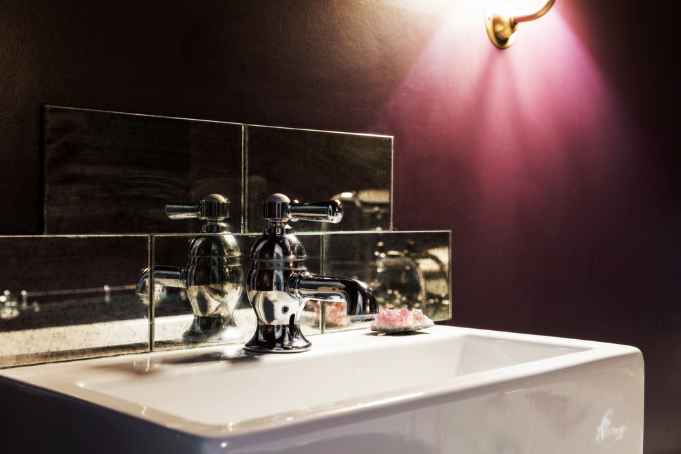 Lantlig inredning av ett litet en-suite badrum, med ett platsbyggt badkar, en toalettstol med separat cisternkåpa, beige kakel, glaskakel, lila väggar, klinkergolv i porslin, ett väggmonterat handfat och flerfärgat golv