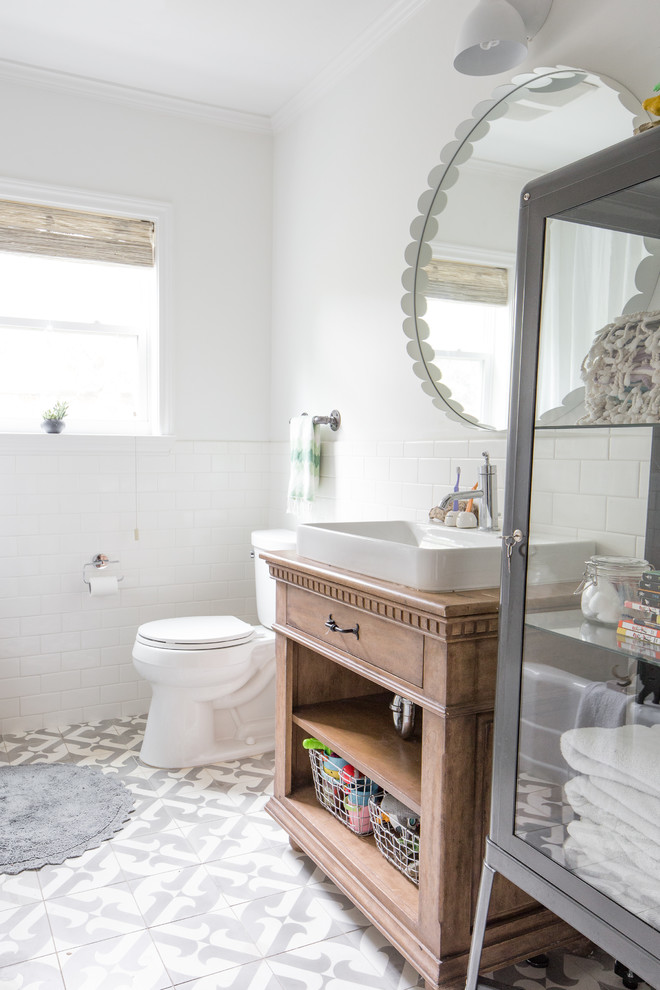This is an example of a traditional family bathroom in Houston with a two-piece toilet, white tiles, ceramic tiles, white walls, cement flooring and a vessel sink.
