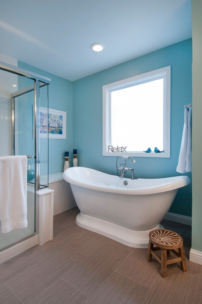 Cette photo montre une grande salle de bain principale bord de mer avec un placard en trompe-l'oeil, des portes de placard blanches, une baignoire indépendante, une douche d'angle, WC séparés, un mur bleu, un sol en carrelage de terre cuite, un lavabo intégré, un plan de toilette en onyx, un sol marron et une cabine de douche à porte battante.
