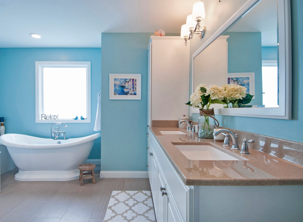 На фото: большая главная ванная комната в морском стиле с фасадами островного типа, белыми фасадами, отдельно стоящей ванной, угловым душем, раздельным унитазом, синими стенами, полом из мозаичной плитки, монолитной раковиной, столешницей из оникса, коричневым полом и душем с распашными дверями