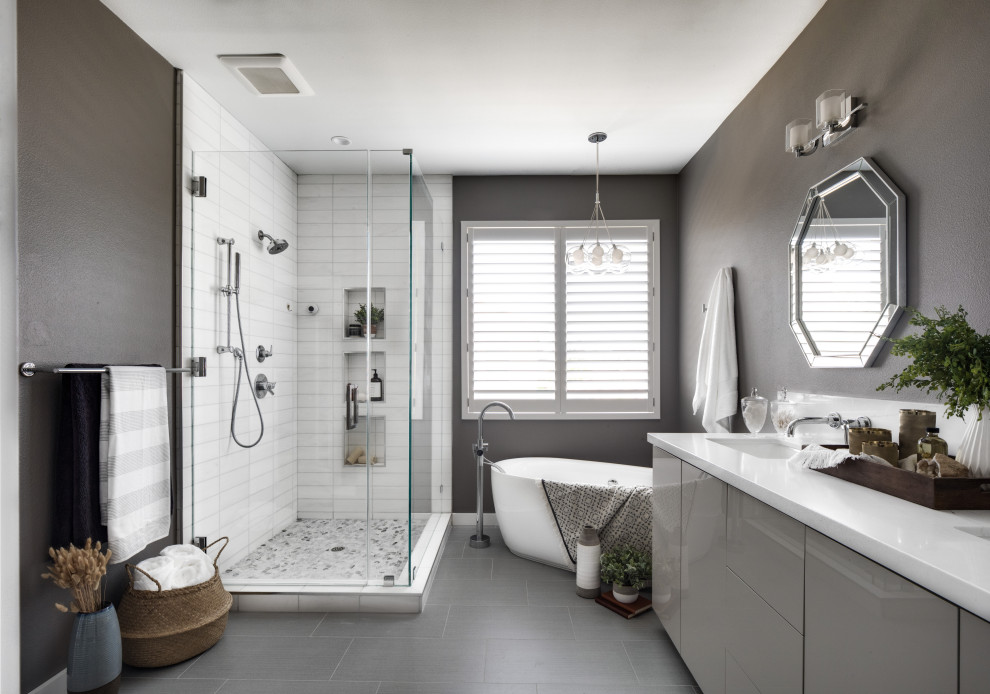 Inspiration for a medium sized contemporary ensuite bathroom in Orange County with flat-panel cabinets, grey cabinets, a freestanding bath, a corner shower, a two-piece toilet, white tiles, marble tiles, grey walls, porcelain flooring, a submerged sink, engineered stone worktops, grey floors, a hinged door, white worktops, an enclosed toilet, double sinks and a built in vanity unit.