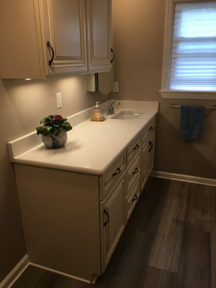 Example of a small classic beige tile and porcelain tile vinyl floor, gray floor and single-sink bathroom design in New York with raised-panel cabinets, a two-piece toilet, an undermount sink, marble countertops, a hinged shower door, white countertops and a built-in vanity