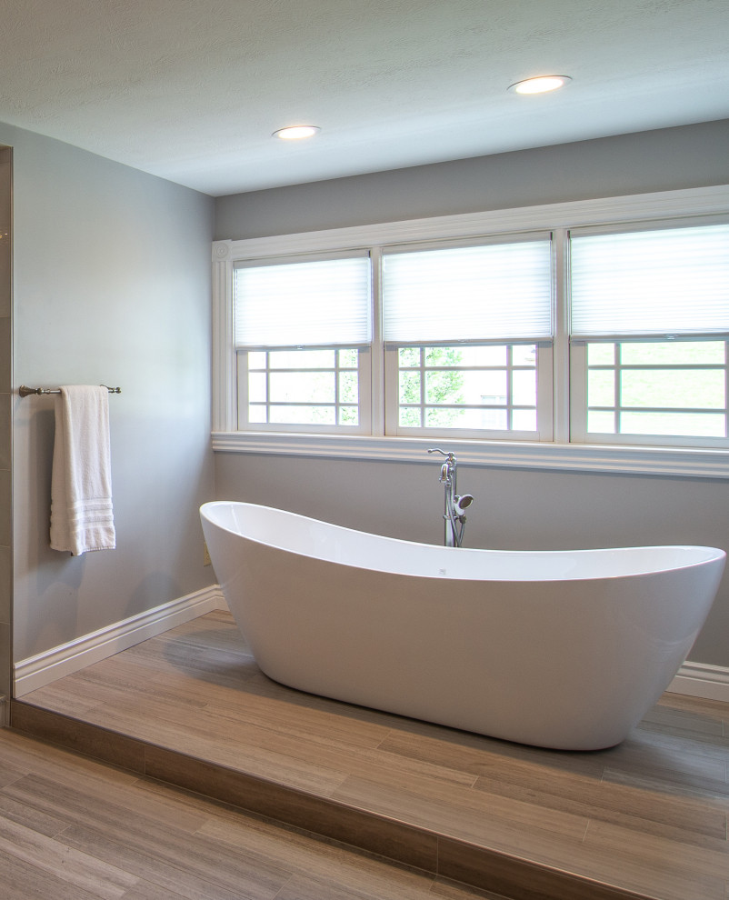 Badezimmer mit freistehender Badewanne, Kalkstein und Falttür-Duschabtrennung in Sonstige