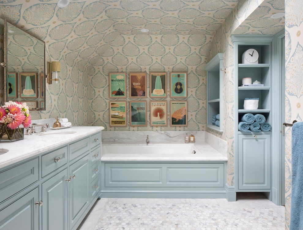 Cette photo montre une grande salle de bain principale chic avec un placard à porte affleurante, des portes de placard bleues, une baignoire encastrée, un mur multicolore, un sol en marbre, un lavabo encastré, un sol blanc, un plan de toilette blanc, un plafond en papier peint et du papier peint.