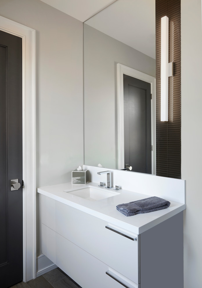 Design ideas for a medium sized contemporary shower room bathroom in Toronto with flat-panel cabinets, white cabinets, an alcove bath, a shower/bath combination, a one-piece toilet, grey tiles, porcelain tiles, grey walls, porcelain flooring, a submerged sink, solid surface worktops, grey floors and a hinged door.