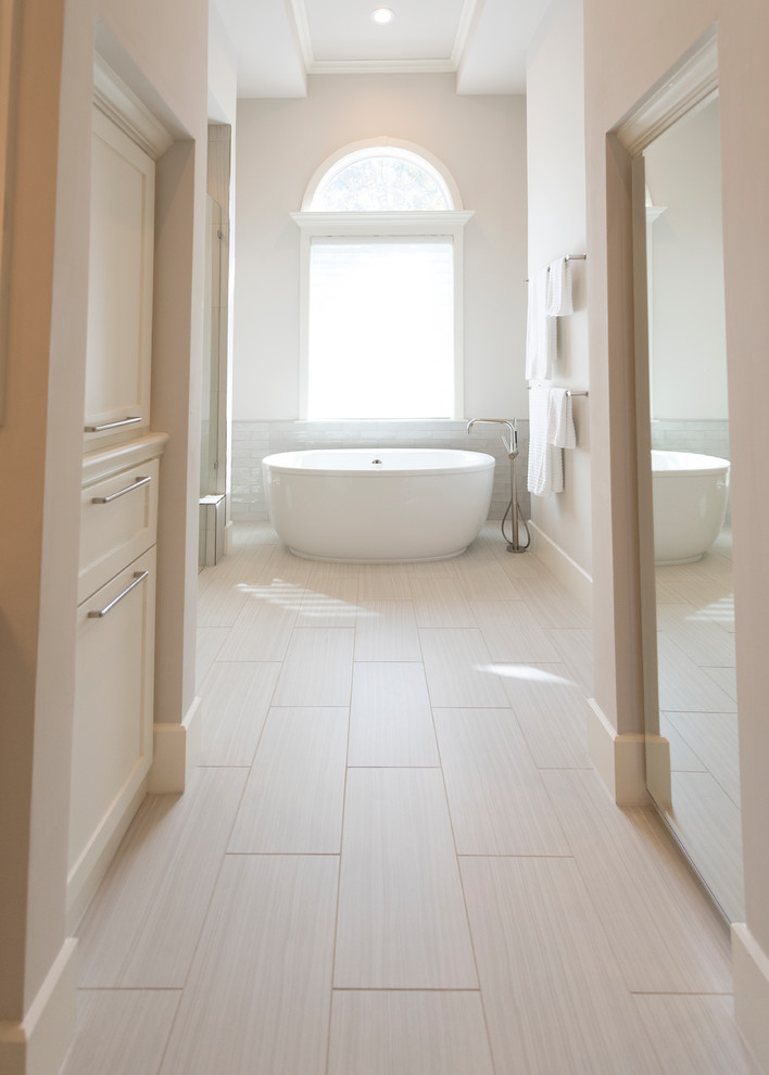 Immagine di una grande stanza da bagno padronale moderna con ante in stile shaker, ante bianche, vasca freestanding, WC a due pezzi, piastrelle bianche, piastrelle in ceramica, pareti beige, pavimento in laminato, lavabo da incasso e pavimento beige