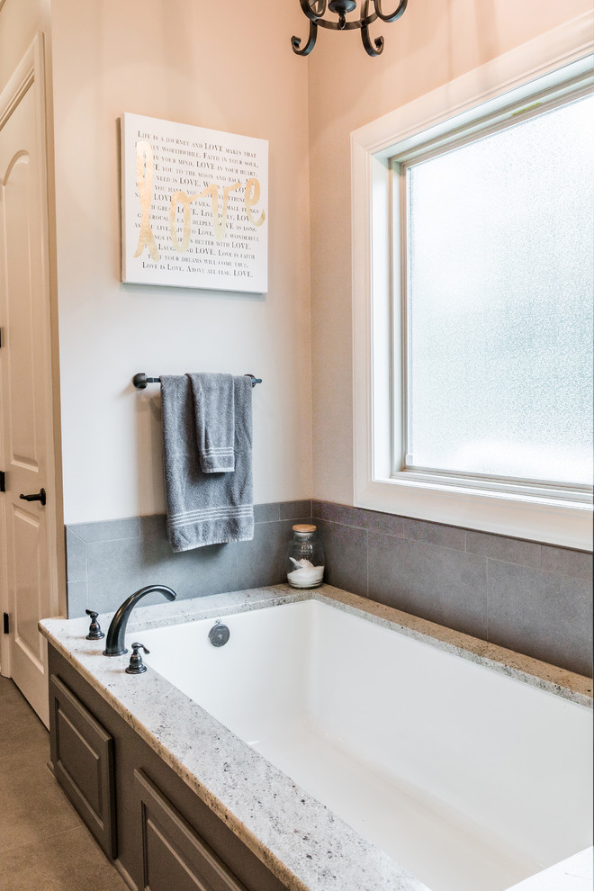 На фото: ванная комната среднего размера в стиле неоклассика (современная классика) с полновстраиваемой ванной, серой плиткой, керамогранитной плиткой, бежевыми стенами, полом из керамогранита и коричневым полом с