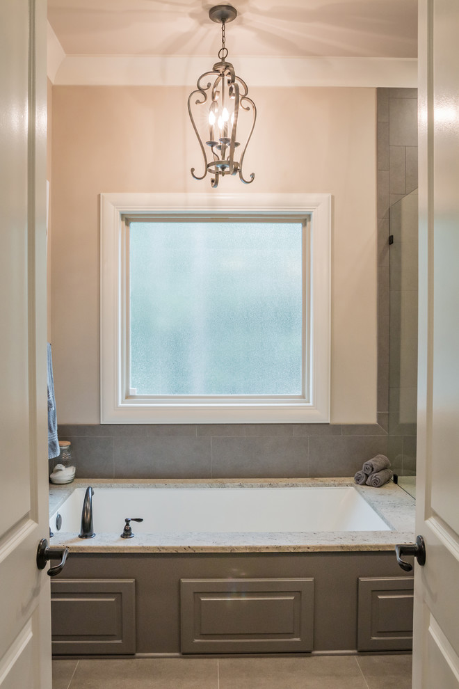 Ejemplo de cuarto de baño clásico renovado de tamaño medio con bañera encastrada sin remate, baldosas y/o azulejos grises, baldosas y/o azulejos de porcelana, paredes beige, suelo de baldosas de porcelana y suelo marrón
