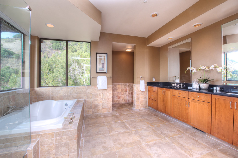 Exemple d'une grande salle de bain principale tendance en bois foncé avec un placard à porte shaker, un plan de toilette en granite, une baignoire posée, une douche ouverte, un carrelage beige, un carrelage de pierre, un mur marron et un sol en travertin.