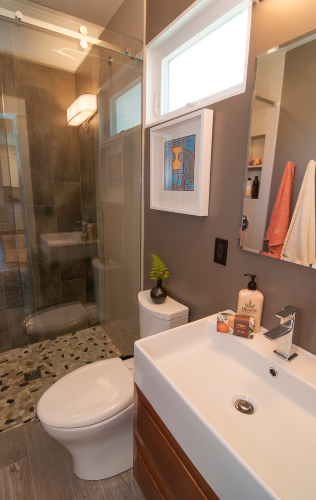 Modelo de cuarto de baño de estilo americano pequeño con ducha a ras de suelo, suelo de baldosas tipo guijarro, paredes marrones, aseo y ducha y lavabo de seno grande