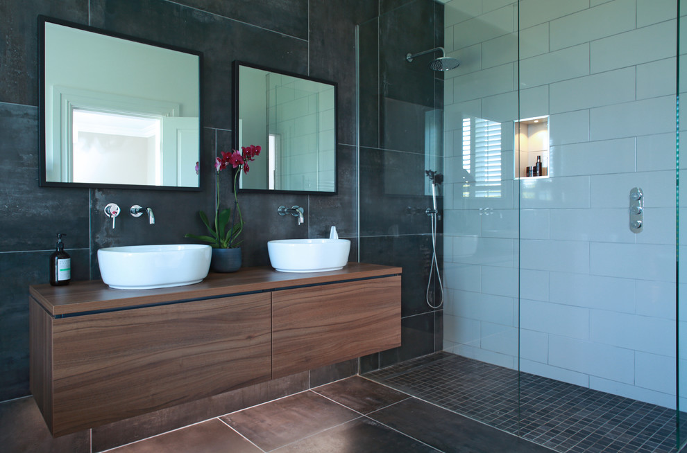 Immagine di una stanza da bagno contemporanea con ante lisce, ante in legno scuro, doccia alcova, piastrelle nere, piastrelle bianche, lavabo a bacinella, top in legno, pavimento nero e top marrone