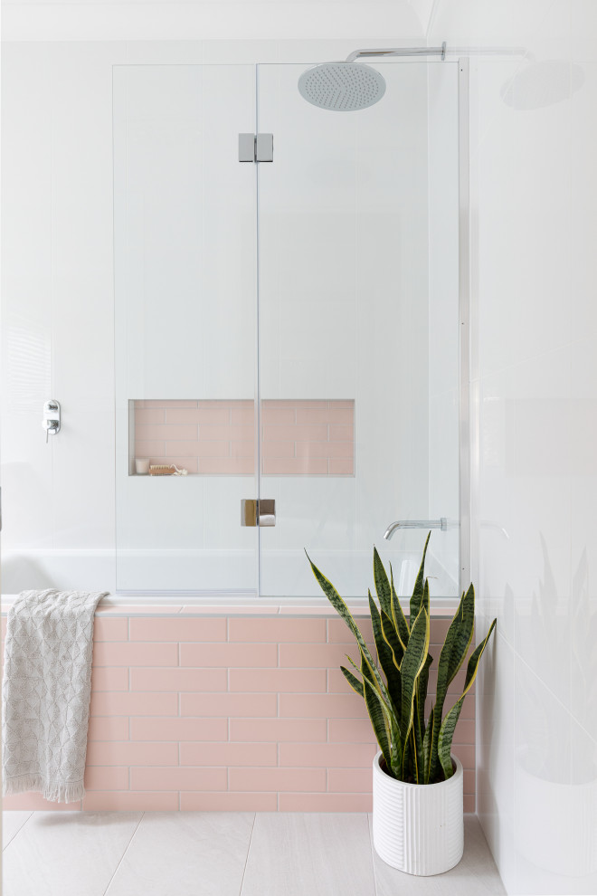 ブリスベンにある小さなコンテンポラリースタイルのおしゃれな子供用バスルーム (ドロップイン型浴槽、シャワー付き浴槽	、ピンクのタイル、白い壁、グレーの床、造り付け洗面台) の写真