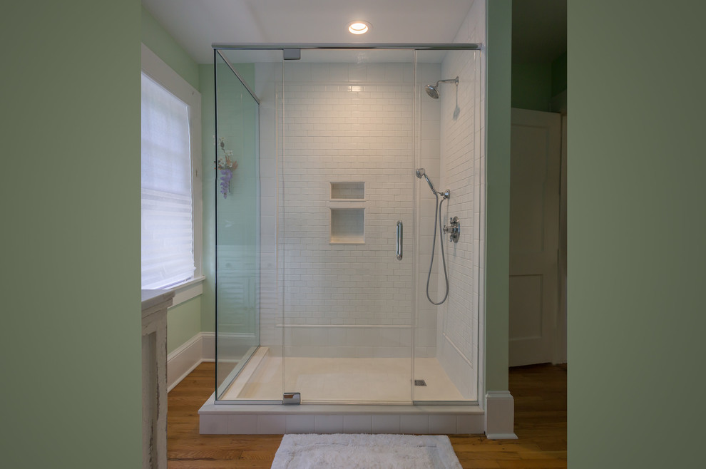 Cette image montre une petite salle de bain principale traditionnelle avec une douche d'angle, un carrelage blanc, des carreaux de céramique, un mur vert, un sol en bois brun, un sol marron et une cabine de douche à porte battante.