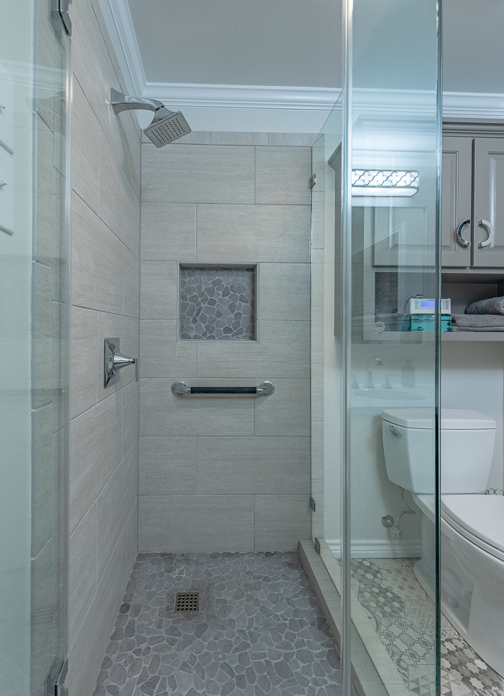 Пример оригинального дизайна: маленькая ванная комната в стиле модернизм с стеклянными фасадами, серыми фасадами, угловым душем, раздельным унитазом, бежевыми стенами, полом из керамической плитки, душевой кабиной, накладной раковиной, столешницей из гранита, разноцветным полом, душем с распашными дверями и белой столешницей для на участке и в саду