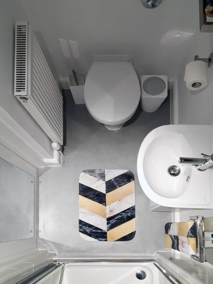 Inspiration för ett litet funkis badrum med dusch, med släta luckor, vita skåp, en kantlös dusch, en vägghängd toalettstol, vit kakel, keramikplattor, vita väggar, betonggolv, ett väggmonterat handfat, grått golv och dusch med gångjärnsdörr