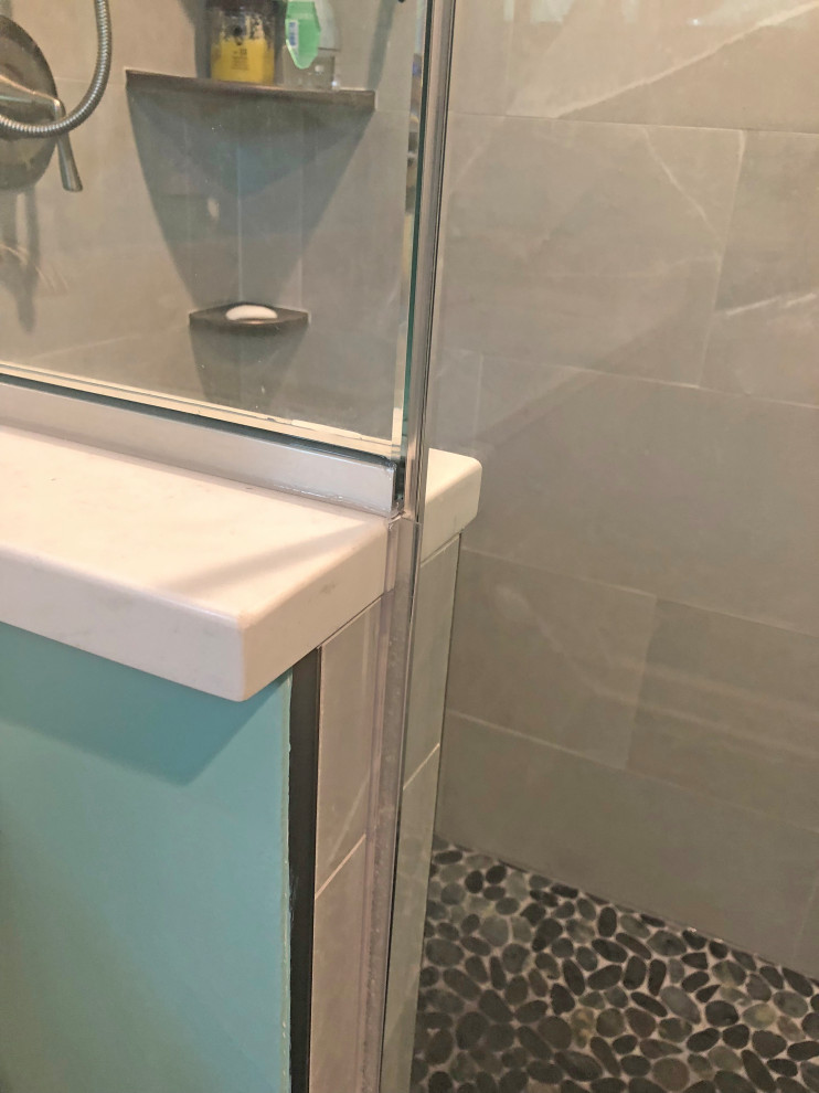 Photo of a small classic ensuite bathroom in Baltimore with shaker cabinets, grey cabinets, a corner shower, a two-piece toilet, grey tiles, porcelain tiles, blue walls, porcelain flooring, a submerged sink, engineered stone worktops, grey floors, a hinged door, white worktops, a shower bench, double sinks and a built in vanity unit.