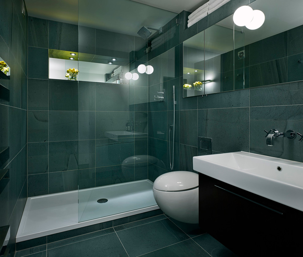 На фото: главная ванная комната среднего размера в современном стиле с подвесной раковиной, плоскими фасадами, темными деревянными фасадами, двойным душем, инсталляцией, зеленой плиткой, каменной плиткой и зелеными стенами с