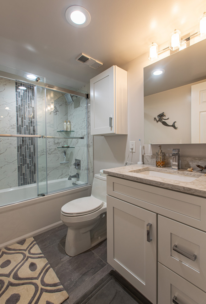Example of a large minimalist master beige tile and porcelain tile porcelain tile and multicolored floor sliding shower door design in DC Metro with shaker cabinets, dark wood cabinets, a two-piece toilet, gray walls, an undermount sink, quartz countertops and beige countertops
