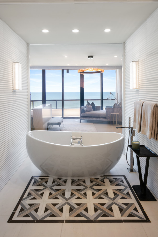 На фото: ванная комната в современном стиле с отдельно стоящей ванной, белой плиткой и бежевым полом с