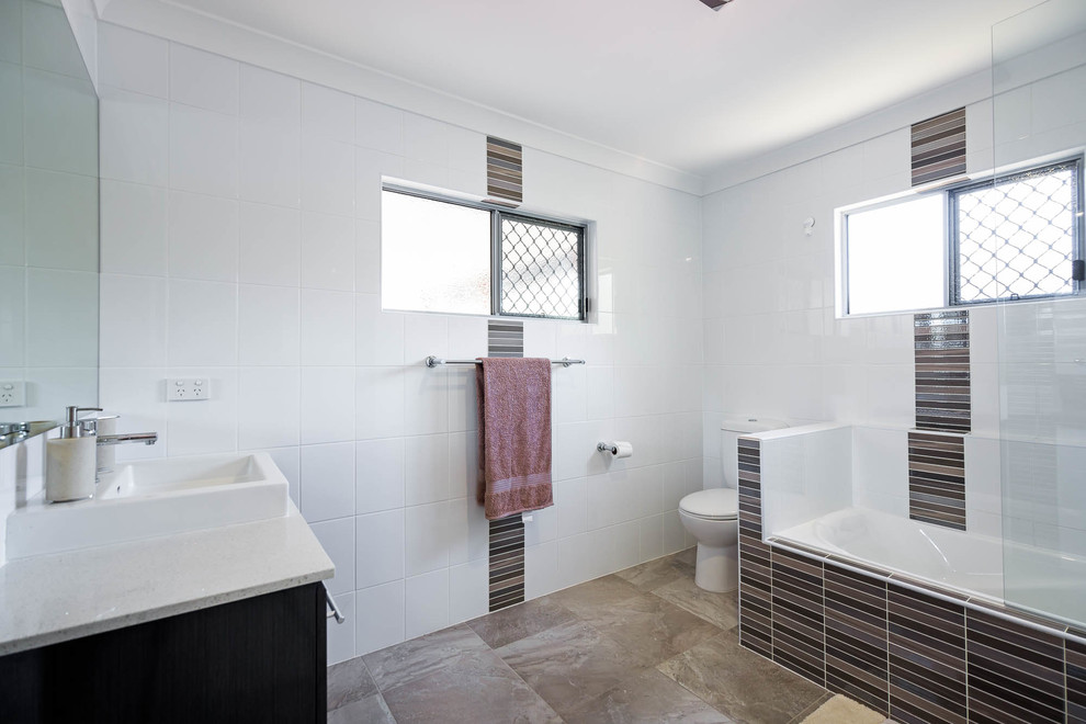 Design ideas for a modern family bathroom in Brisbane with dark wood cabinets, a shower/bath combination, white tiles, a corner bath, porcelain tiles, ceramic flooring and grey floors.