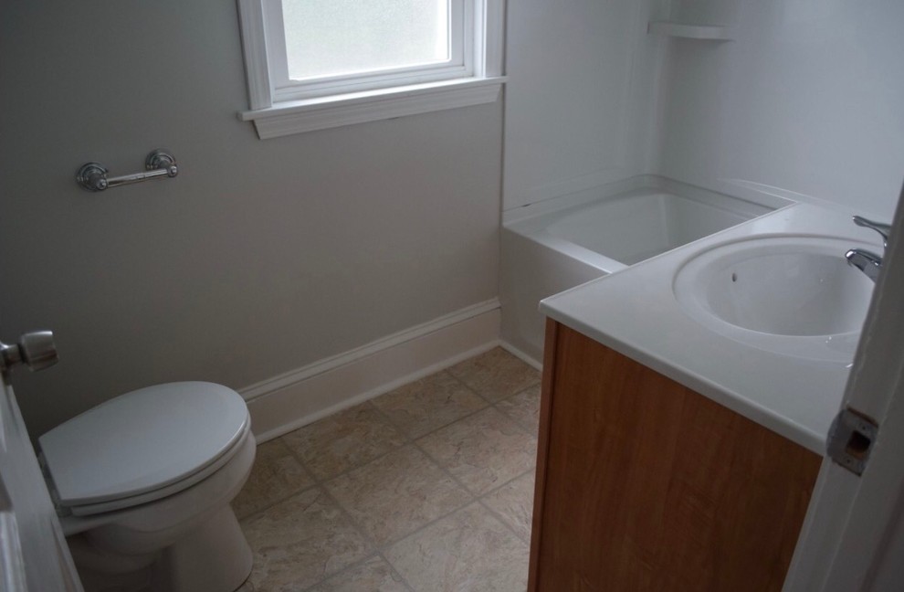 Example of a small classic 3/4 ceramic tile and beige floor bathroom design in New York with medium tone wood cabinets, a two-piece toilet, gray walls, an integrated sink and quartz countertops