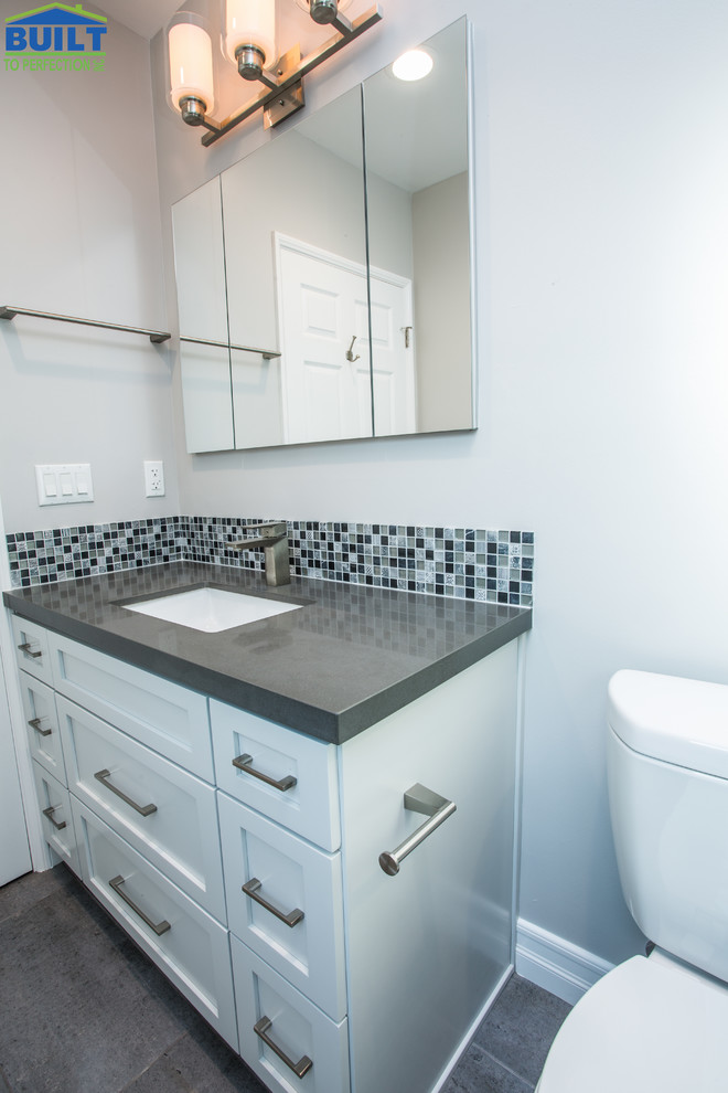Idéer för att renovera ett mellanstort vintage grå grått badrum med dusch, med skåp i shakerstil, vita skåp, en toalettstol med separat cisternkåpa, blå kakel, flerfärgad kakel, glasskiva, vita väggar, klinkergolv i keramik, ett undermonterad handfat, grått golv, en dusch i en alkov och dusch med gångjärnsdörr