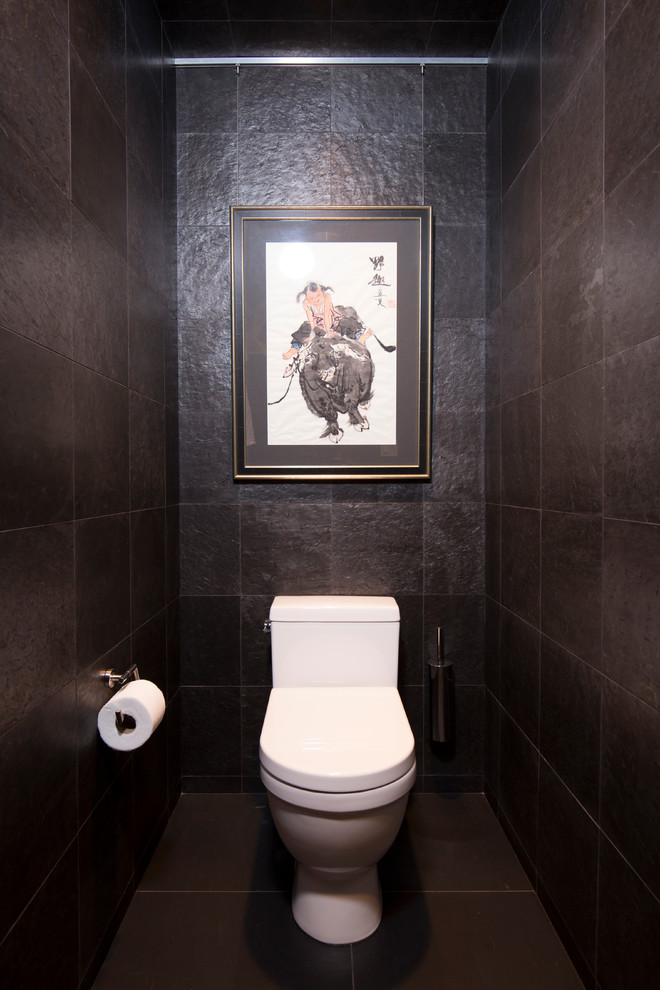 Immagine di un bagno di servizio etnico di medie dimensioni con WC monopezzo, piastrelle nere, piastrelle in pietra, pareti nere, pavimento in ardesia, ante a persiana, ante in legno chiaro, lavabo sottopiano, top in granito e pavimento nero
