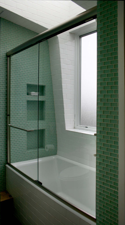 Ispirazione per una stanza da bagno design con piastrelle verdi, piastrelle di vetro, pareti verdi, vasca ad alcova, vasca/doccia e porta doccia scorrevole