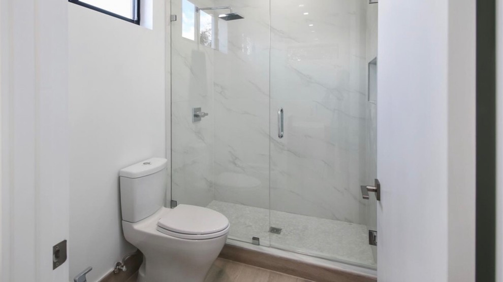 Пример оригинального дизайна: маленькая главная ванная комната в стиле модернизм с плоскими фасадами, коричневыми фасадами, отдельно стоящей ванной, унитазом-моноблоком, белой плиткой, керамической плиткой, разноцветными стенами, полом из ламината, врезной раковиной, столешницей из искусственного кварца, разноцветным полом, душем с распашными дверями и разноцветной столешницей для на участке и в саду