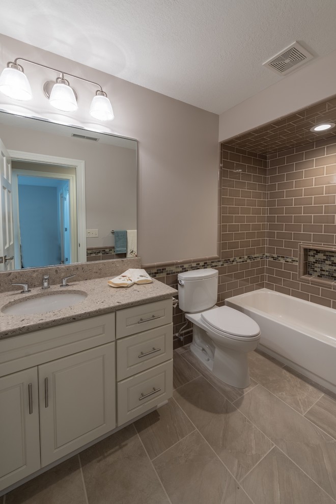 Photo of a medium sized traditional shower room bathroom in Minneapolis with raised-panel cabinets, white cabinets, an alcove bath, a shower/bath combination, a two-piece toilet, brown tiles, metro tiles, beige walls, porcelain flooring, a submerged sink, engineered stone worktops, beige floors and a shower curtain.