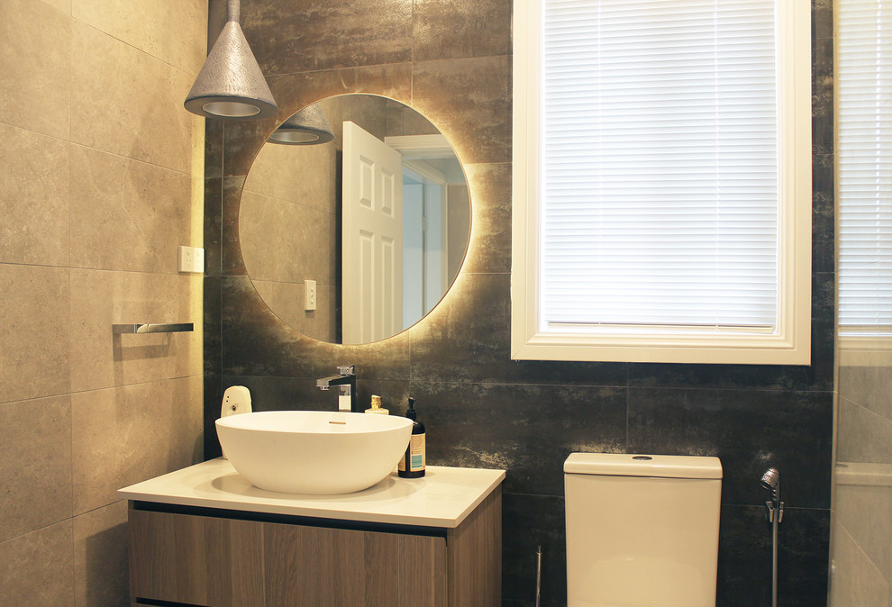 На фото: маленькая ванная комната в современном стиле с плоскими фасадами, фасадами цвета дерева среднего тона, душем в нише, унитазом-моноблоком, черной плиткой, керамогранитной плиткой, серыми стенами, полом из керамогранита, настольной раковиной, столешницей из искусственного кварца, серым полом, душем с распашными дверями и белой столешницей для на участке и в саду