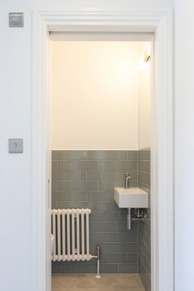 Immagine di una piccola stanza da bagno minimalista con WC sospeso, piastrelle multicolore, piastrelle in ceramica, pareti multicolore, pavimento in cementine, lavabo sospeso, pavimento grigio, toilette e un lavabo