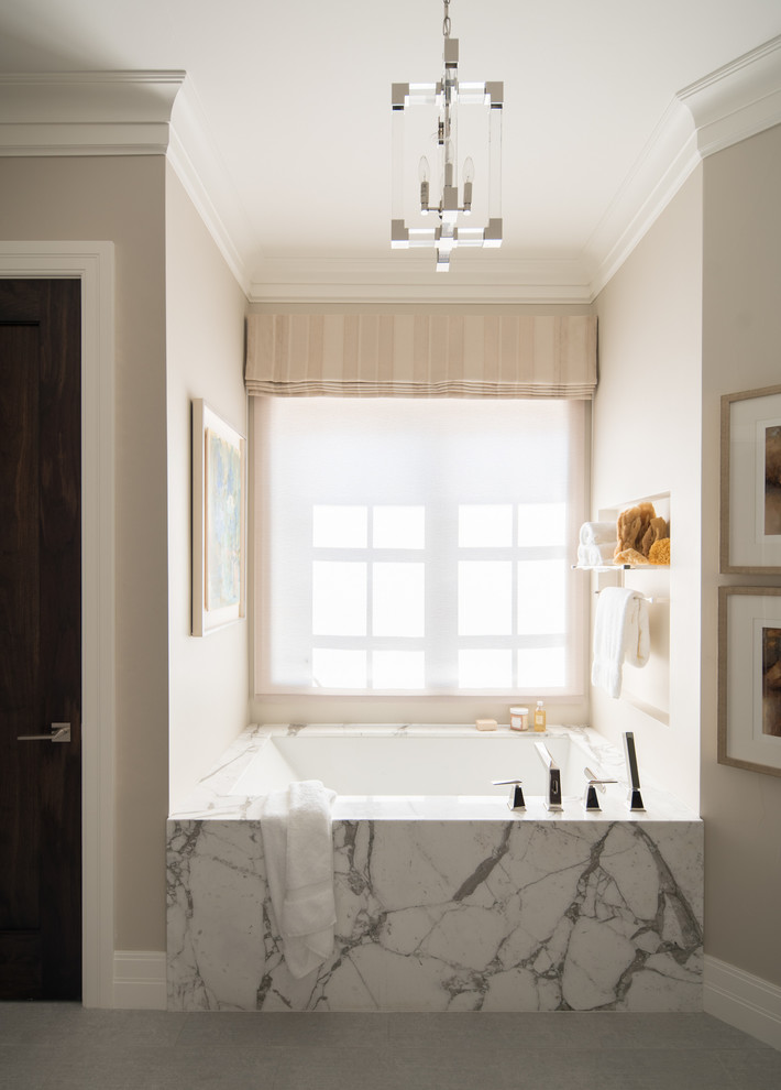 Réalisation d'une salle de bain tradition avec une baignoire encastrée, un mur beige et un sol gris.