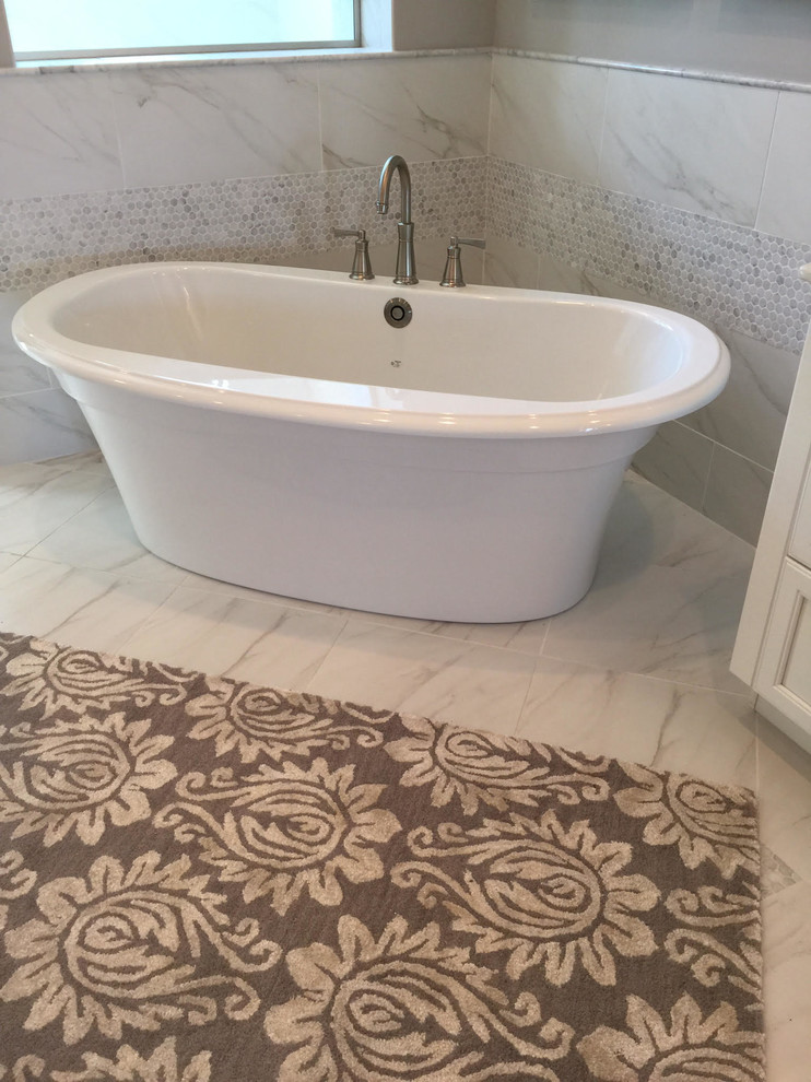Idée de décoration pour une salle de bain principale design avec un placard avec porte à panneau encastré, des portes de placard blanches, une baignoire indépendante, mosaïque, un mur gris, un sol en marbre et un sol blanc.