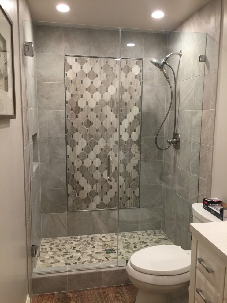 Immagine di una stanza da bagno minimalista con ante bianche, doccia alcova e piastrelle grigie