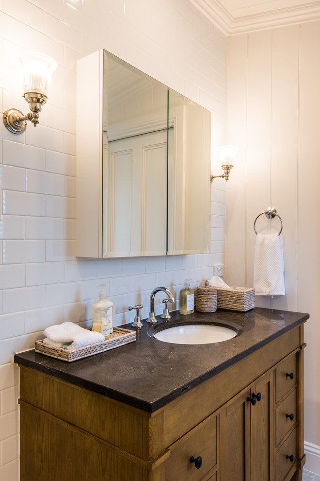 Klassisk inredning av ett mellanstort badrum med dusch, med skåp i shakerstil, skåp i mellenmörkt trä, ett platsbyggt badkar, en dusch/badkar-kombination, en toalettstol med hel cisternkåpa, vit kakel, tunnelbanekakel, vita väggar, klinkergolv i keramik, ett undermonterad handfat, marmorbänkskiva, grått golv och dusch med gångjärnsdörr