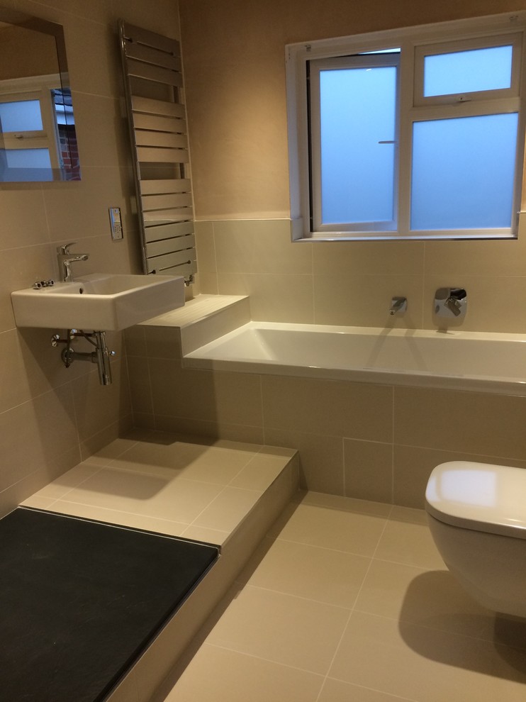 Esempio di una stanza da bagno design di medie dimensioni con lavabo sospeso, WC sospeso, piastrelle beige, piastrelle in gres porcellanato, pareti beige e pavimento in gres porcellanato