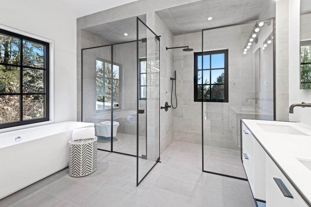 Réalisation d'une salle de bain urbaine avec des portes de placard blanches, un carrelage gris, un plan de toilette en quartz modifié et un plan de toilette blanc.
