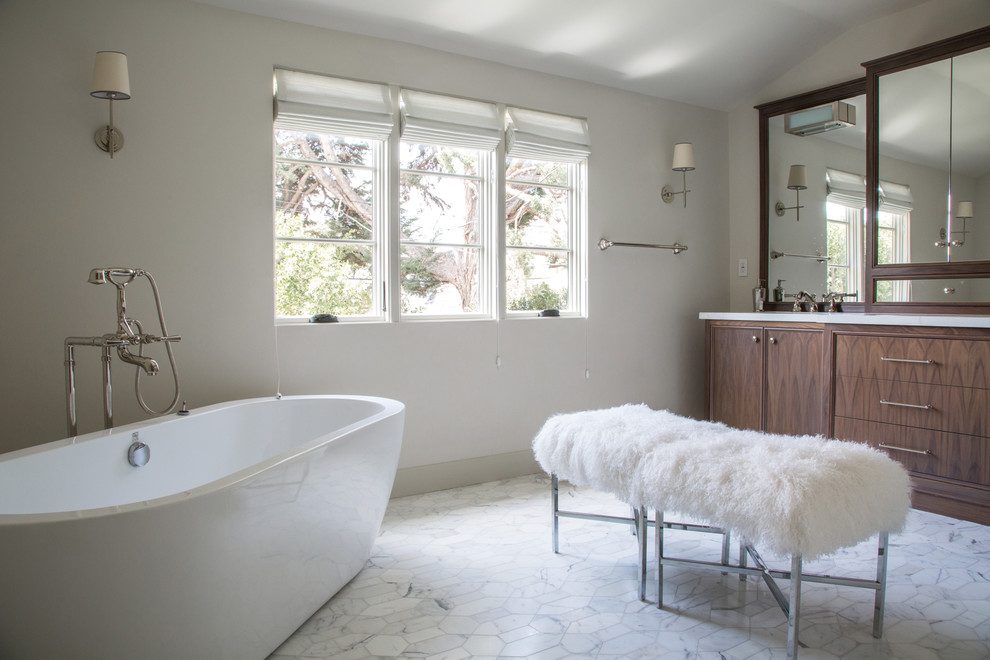 На фото: ванная комната в стиле неоклассика (современная классика) с темными деревянными фасадами, мраморной столешницей, отдельно стоящей ванной, белой плиткой, каменной плиткой, мраморным полом и плоскими фасадами