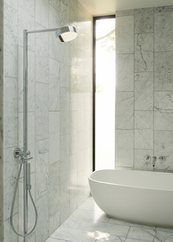This is an example of a modern wet room bathroom in Houston with a freestanding bath, white tiles, white walls, white floors and an open shower.