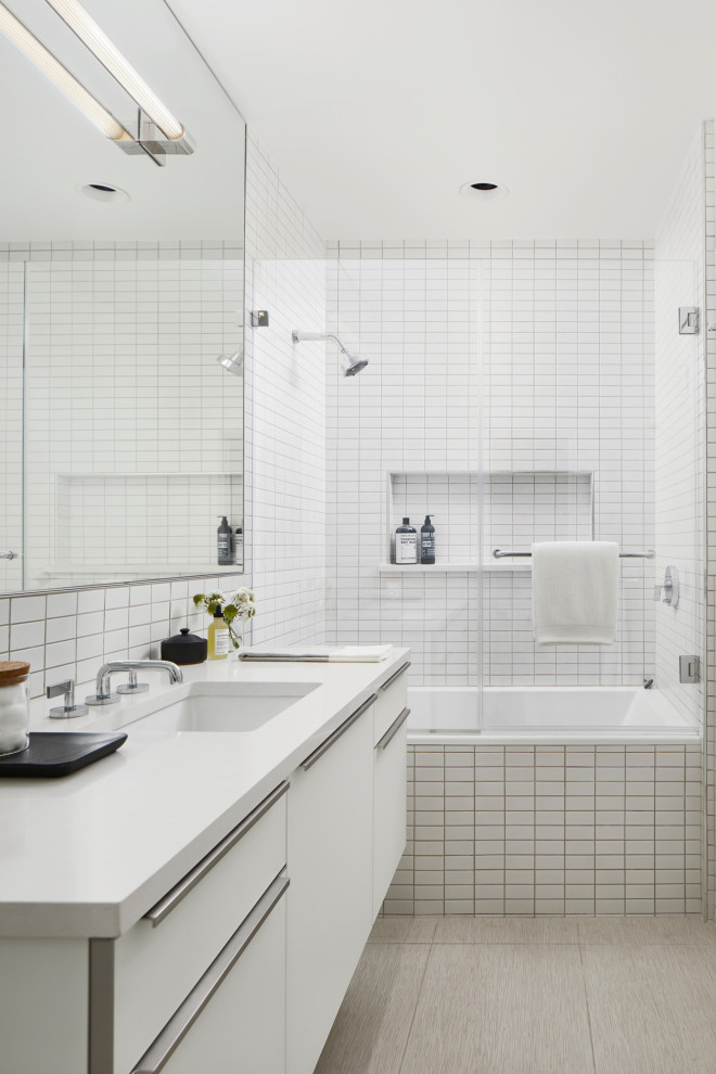 Inspiration för ett litet funkis vit vitt badrum med dusch, med släta luckor, vita skåp, en dusch/badkar-kombination, ett undermonterad handfat, ett badkar i en alkov, vit kakel, beiget golv och dusch med gångjärnsdörr